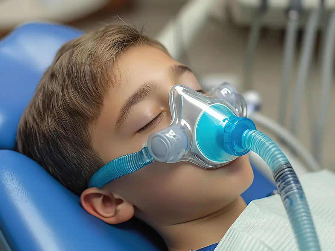 A young patient resting comfortably in the dental chair with a nitrous oxide mask over the nose