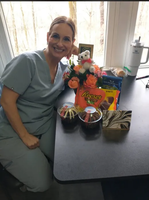 A team member with flowers, treats, and a teddy bear at a celebration table